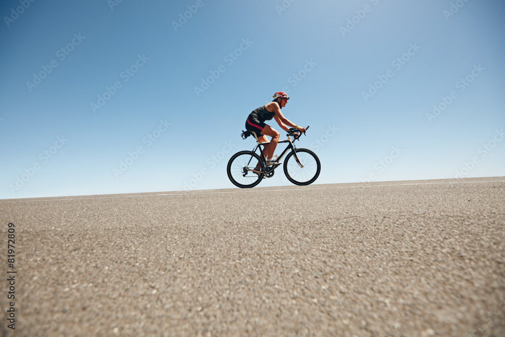 Fototapeta premium Female cyclist on a country road training for triathlon