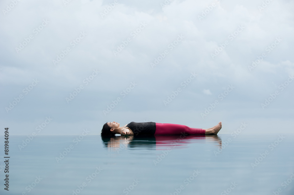 Group of women practicing yoga exercise at the beach, doing meditation  lotus pose near the water. Stock Photo by trimarchi_photo