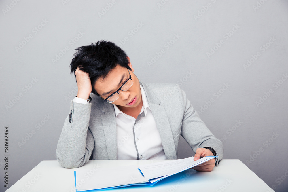 Businessman sitting at the table and reading papers in office Businessman sitting at the table and reading papers in office