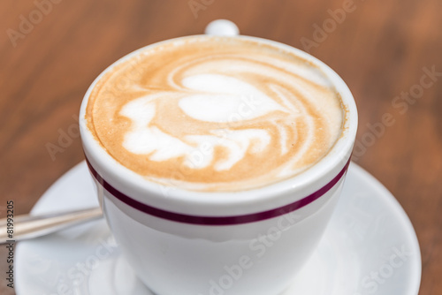 White Cup Of Coffee With Heart Pattern On Wooden Table
