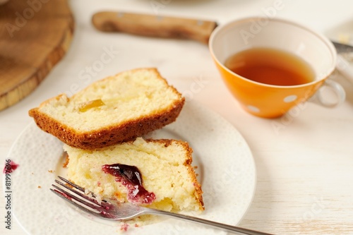 Mascarpone cake slice, cup of tea in orange teacup, table knife,