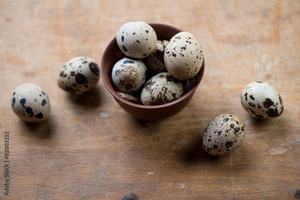 Raw quail eggs over rustic wooden background, high angle view Raw quail eggs over rustic wooden background, high angle view