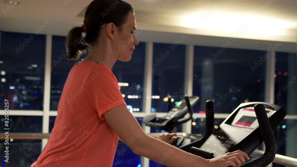 Young woman riding stationary bike in gym at night Young woman riding stationary bike in gym at night