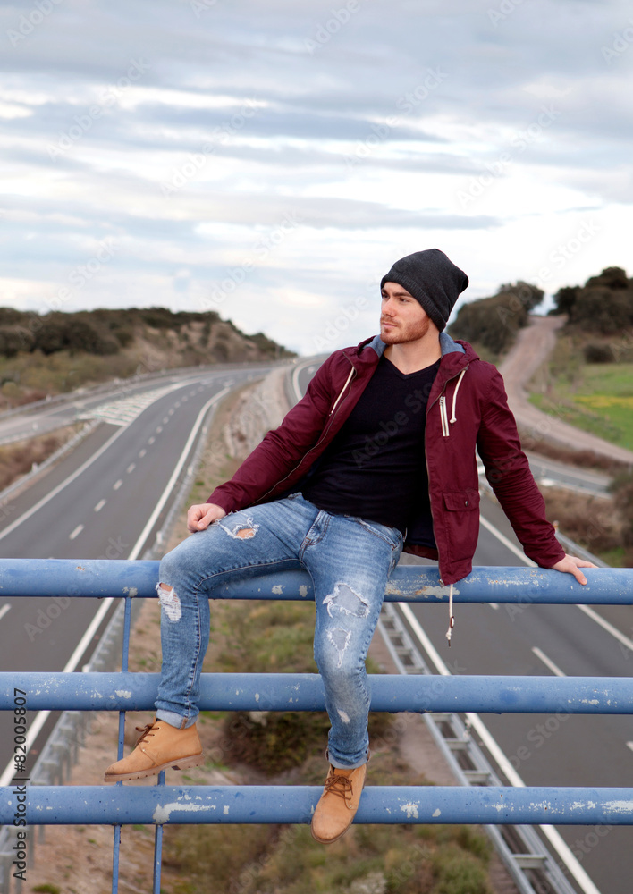 Handsome man at the top of a bridge over a highway Handsome man at the top of a bridge over a highway