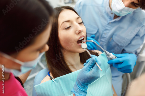 Inspection of the teeth of the girl with the help of a mirror.