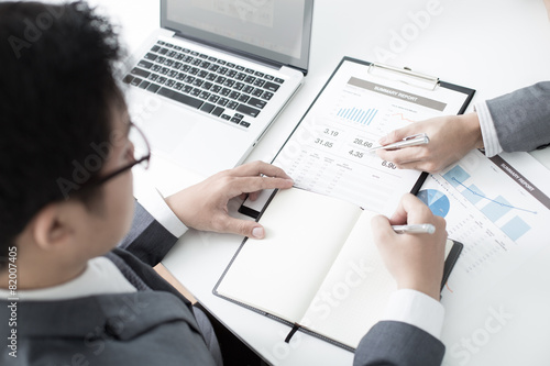 Two businessmen looking at report and having a discussion in off