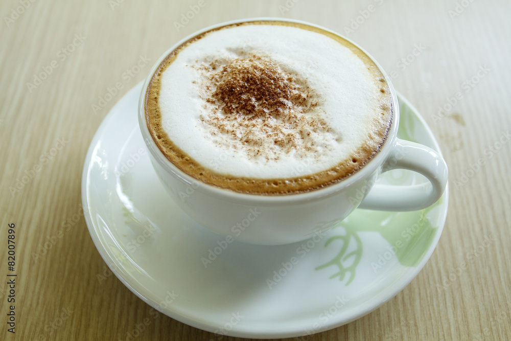 A cup of coffee with heart pattern in a white cup on wooden back A cup of coffee with heart pattern in a white cup on wooden back