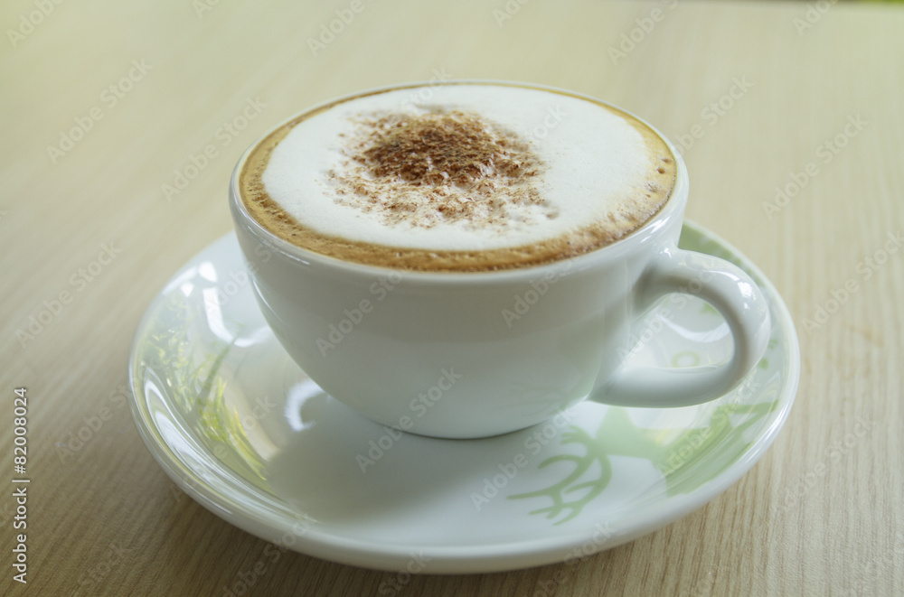 A cup of coffee with heart pattern in a white cup on wooden back A cup of coffee with heart pattern in a white cup on wooden back