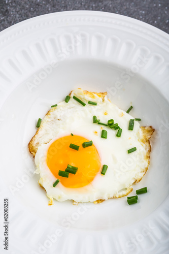 Fried egg with chives on white plate