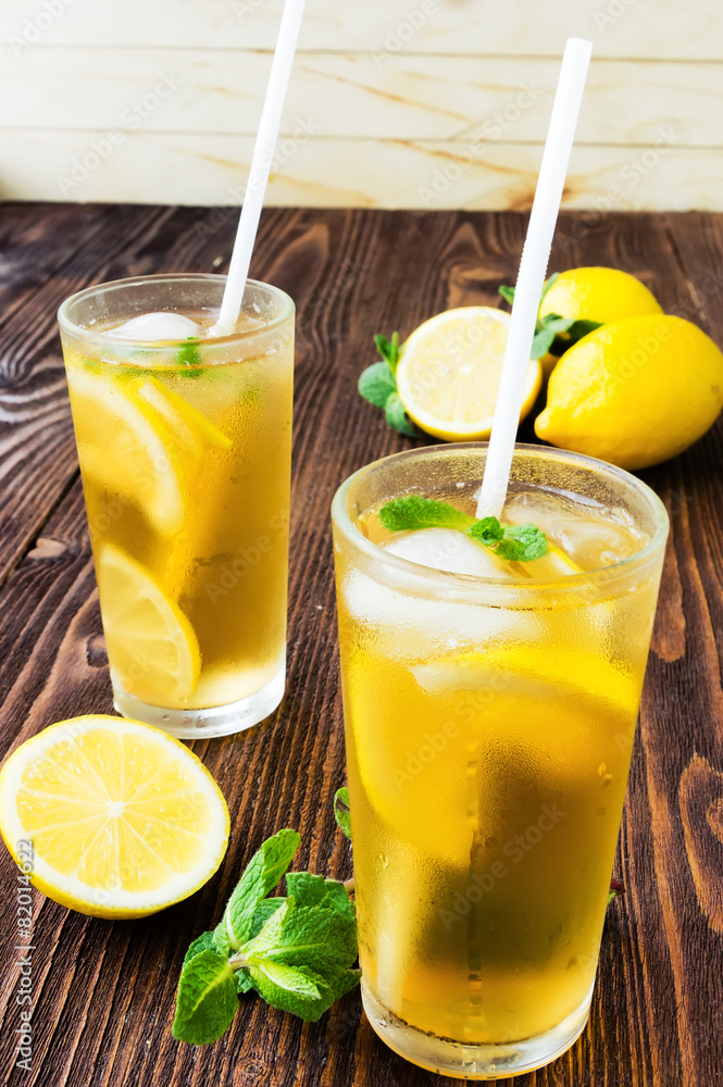 Two glasses of ice tea with ice-cubes on wooden table Two glasses of ice tea with ice-cubes on wooden table