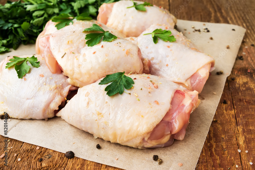 Raw chicken thighs with parsley on wooden table Raw chicken thighs with parsley on wooden table