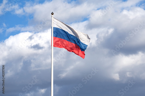 Russian flag on the flagpole waving on cloudy sky