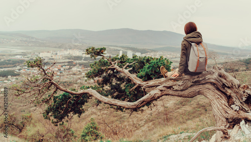 Traveler woman sitting on a tree