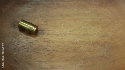 Wallpaper Mural Single bullet cartridge falling on wooden floor 4K UHD Torontodigital.ca