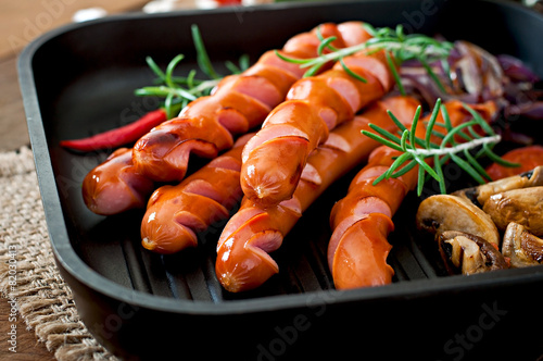Grilled sausages with vegetables on a frying pan