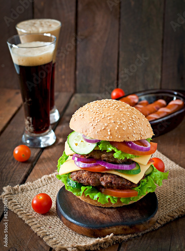 Big juicy hamburger with vegetables and beef on a wooden table