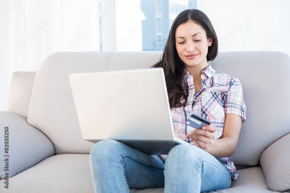 Pretty brunette sitting on couch and shopping online Pretty brunette sitting on couch and shopping online