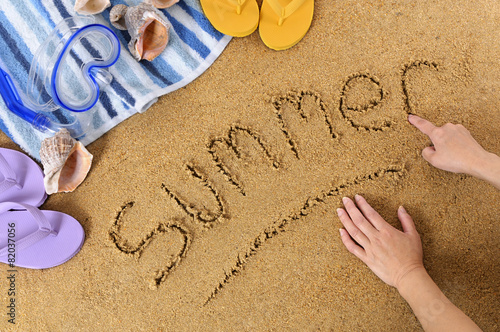 Summer word message child hands writing written in sand on a tropical beach with seashells and accessories holiday vacation photo