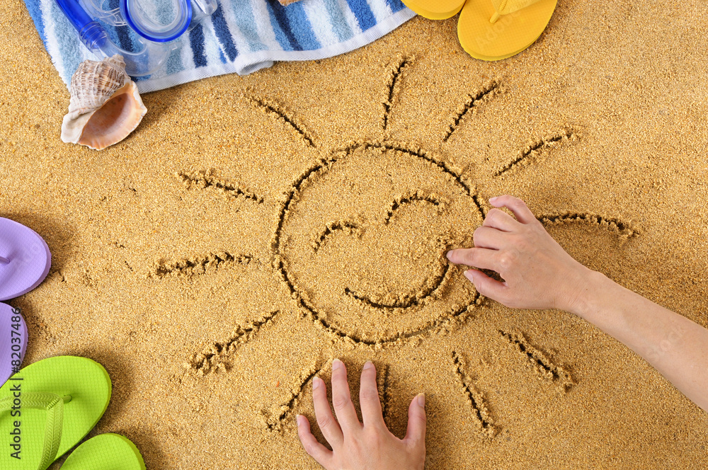 Smiling sun happy smiley face drawing drawn in sand with child hands on a tropical beach with seashells and accessories summer holiday vacation photo