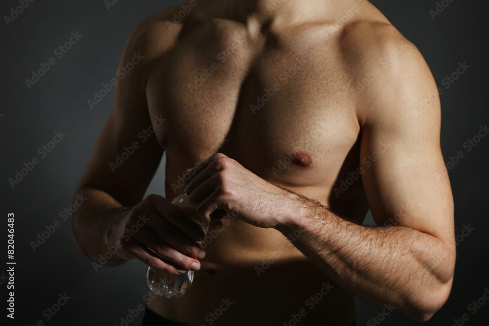 Muscle young man holding bottle of water on black background Muscle young man holding bottle of water on black background