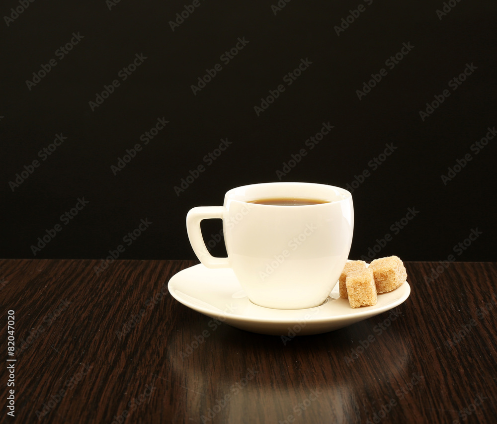 Cup of coffee with lump sugar on wooden table, on dark background Cup of coffee with lump sugar on wooden table, on dark background