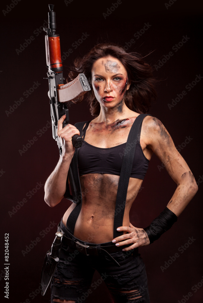 Beautiful young woman holding an automatic assault rifle. Beautiful young woman holding an automatic assault rifle.
