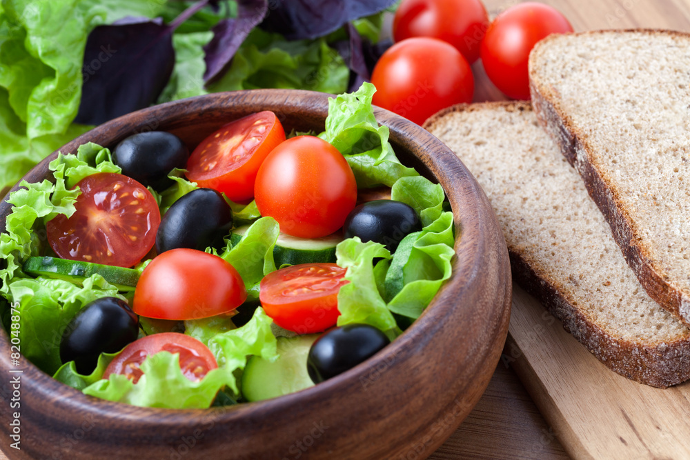 Spring vegetarian salad with tomato and olives on rustic backgro Spring vegetarian salad with tomato and olives on rustic backgro