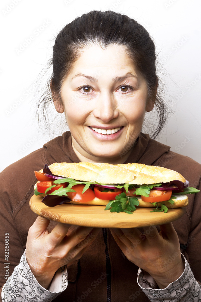 Woman with a sandwich with tomatoes, red onion and arugula. Woman with a sandwich with tomatoes, red onion and arugula.
