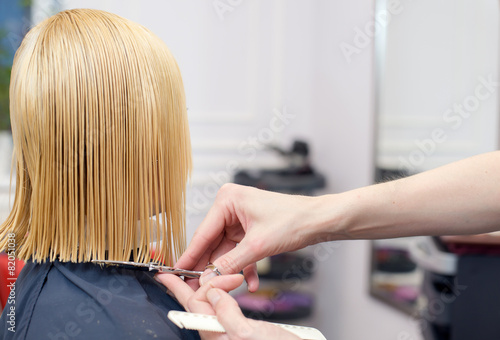 A hairdresser making a haircut for a blonde girl