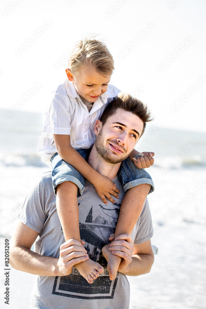 father carries his son on his shoulders to the sea father carries his son on his shoulders to the sea