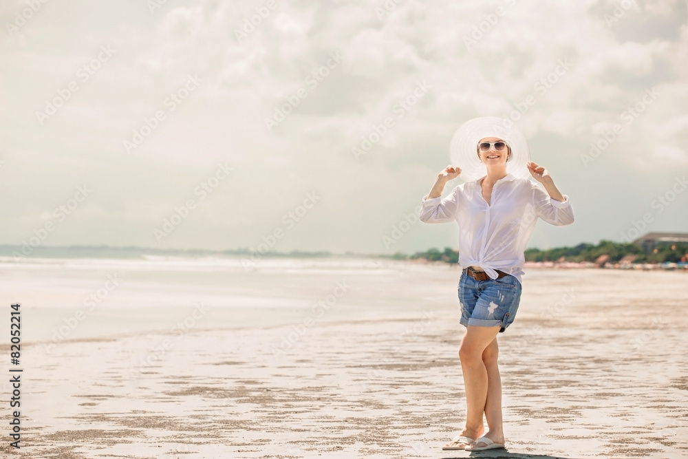 Beautifil young woman walking along the beach at sunny day