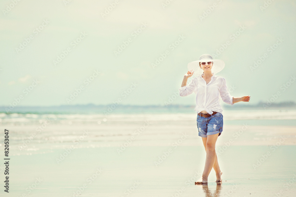 Beautifil young woman walking along the beach at sunny day