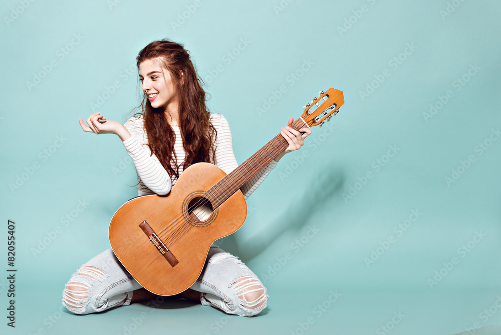 Young woman playing guitar while sitting on rooftop in city stock photo