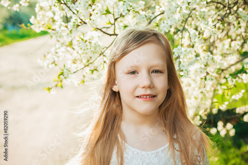 Little girl in a white dress on a sunny spring garden