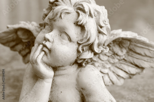 Fotografie, Obraz detail of looking up cherub figurine in sepia