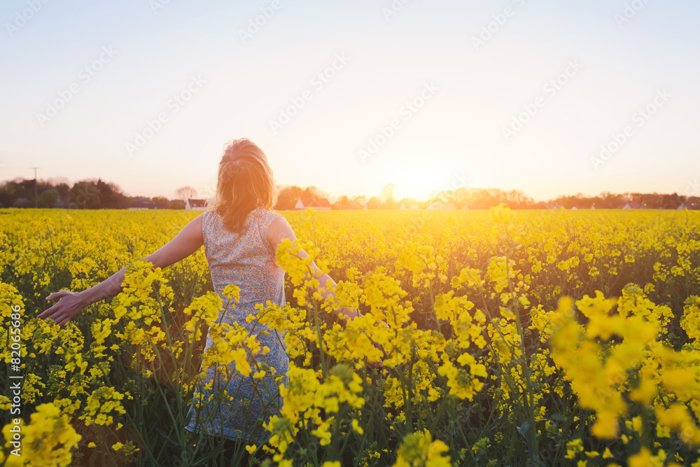 Fototapeta premium happy young woman enjoing summer in yellow field at sunset