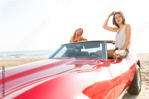 girls at beach in sports car convertible having