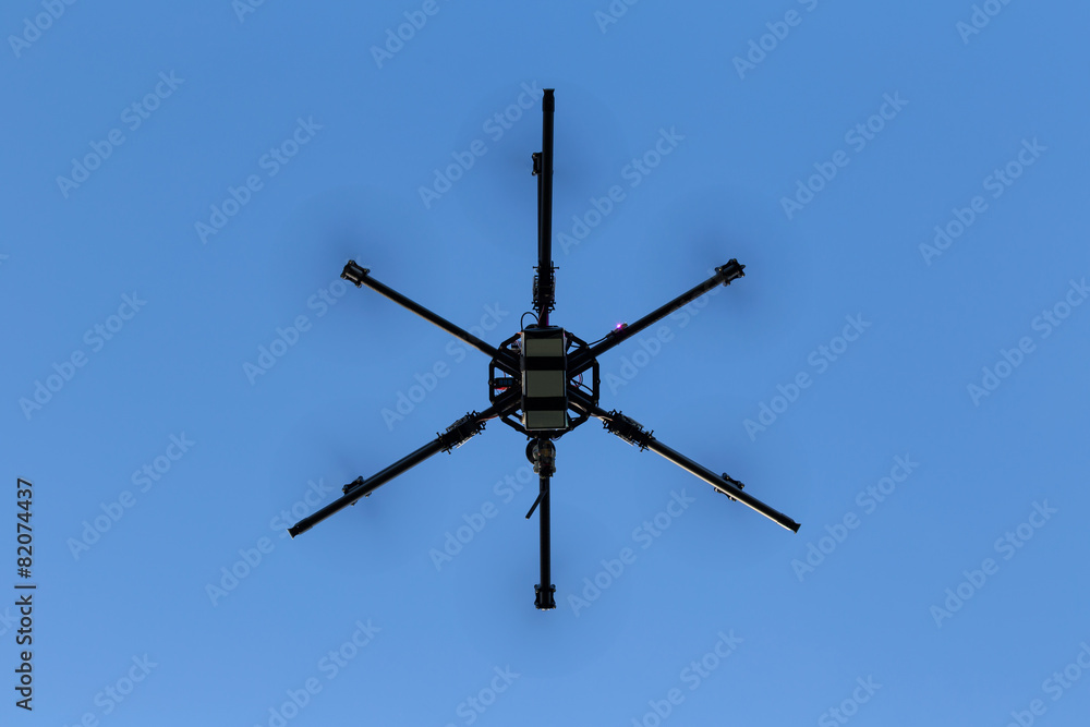 Professional drone hexacopter flying on blue sky Professional drone hexacopter flying on blue sky
