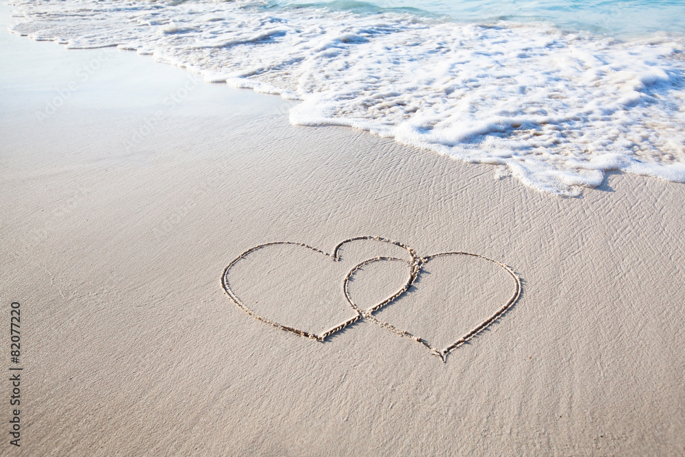 two hearts drawn on perfectly white sand of paradise beach