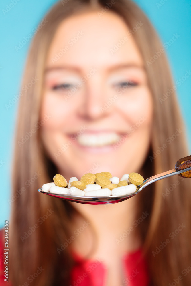 Young woman eating pills on a spoon Young woman eating pills on a spoon