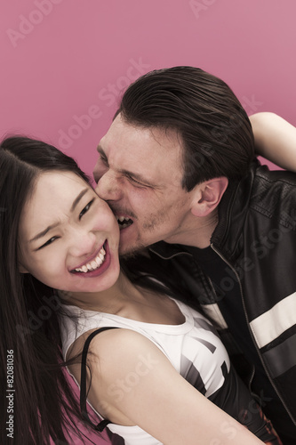 Funny man portrait biting the cheek of his girlfriend