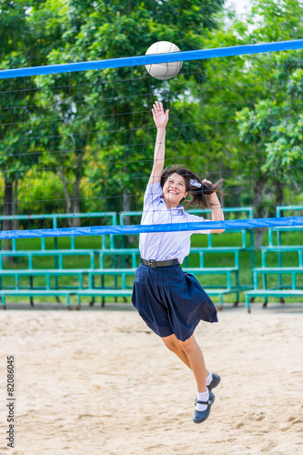 Cute Thai schoolgirl is playing beach volleyball in school unifo