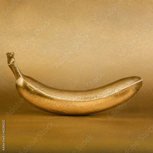 Whole golden banana on gold background
