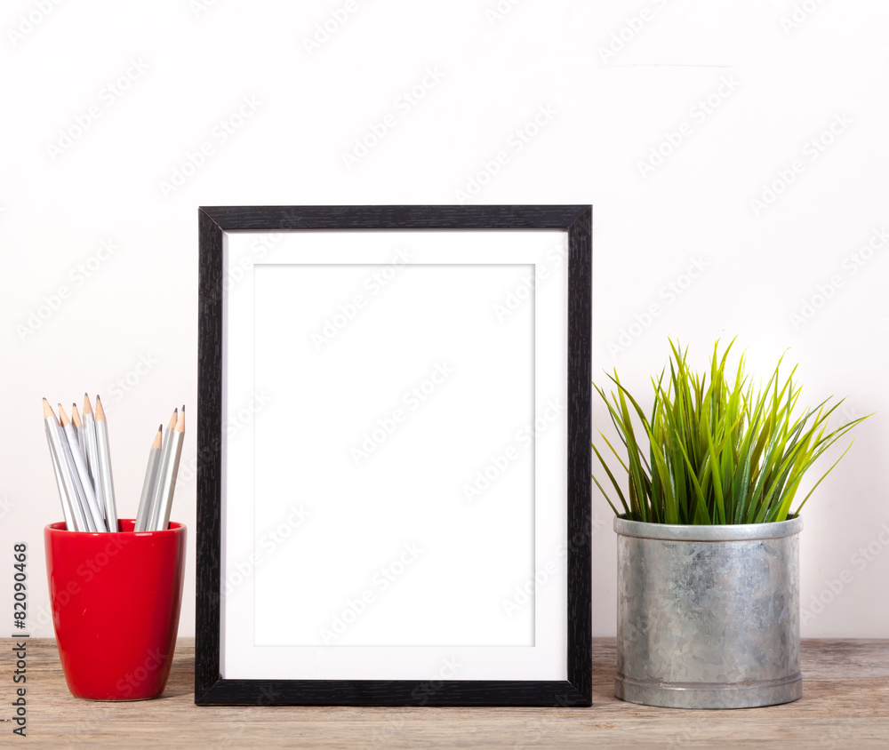 picture frame with office items and pot planr on wooden table