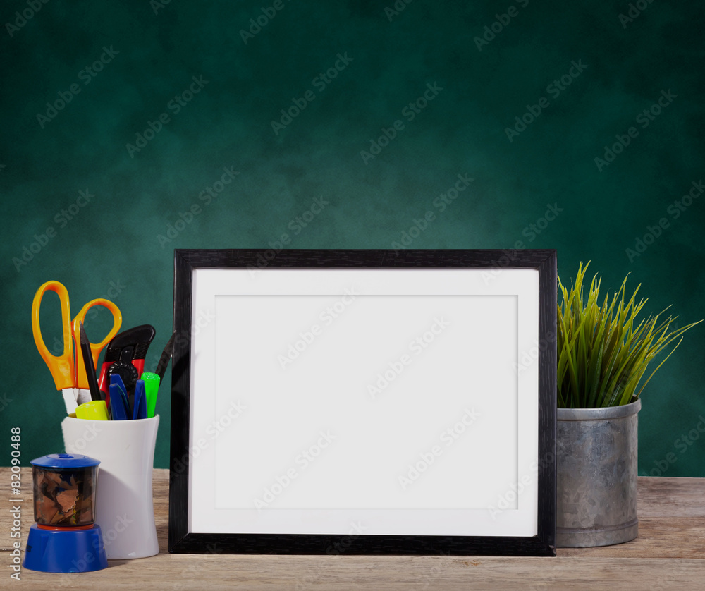 picture frame on green background with office items and pot pla
