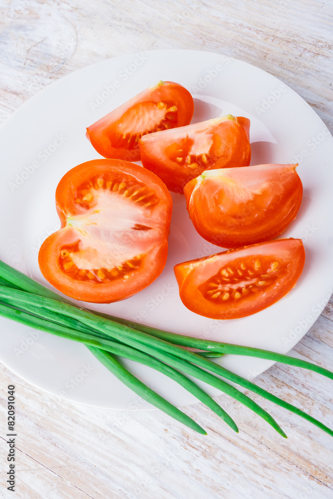 sliced tomato and chives on a white plate sliced tomato and chives on a white plate