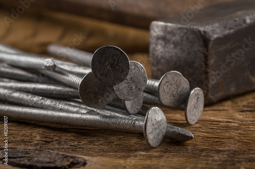 Vintage hammer with nails on wood background