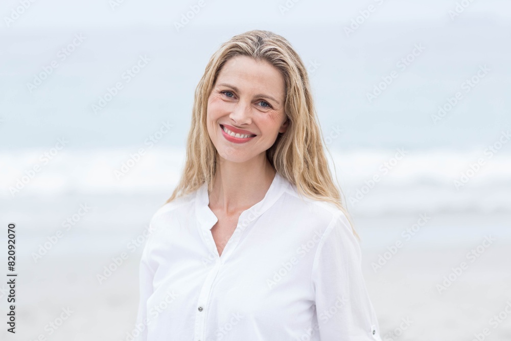 Smiling blonde standing by the sea and looking at camera Smiling blonde standing by the sea and looking at camera