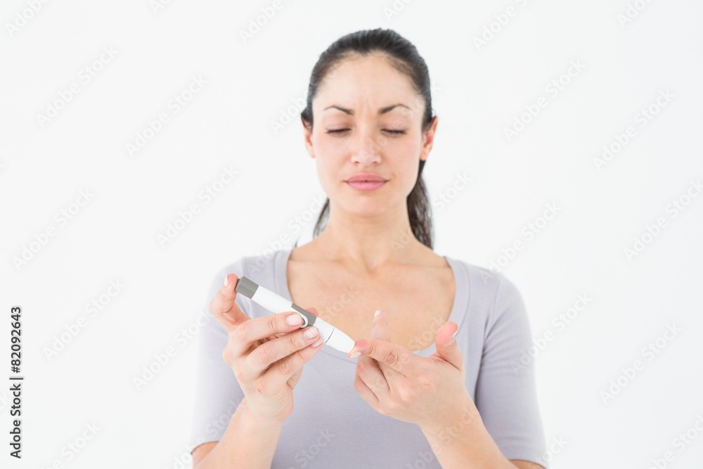 Diabetic brunette using blood glucose monitor Diabetic brunette using blood glucose monitor