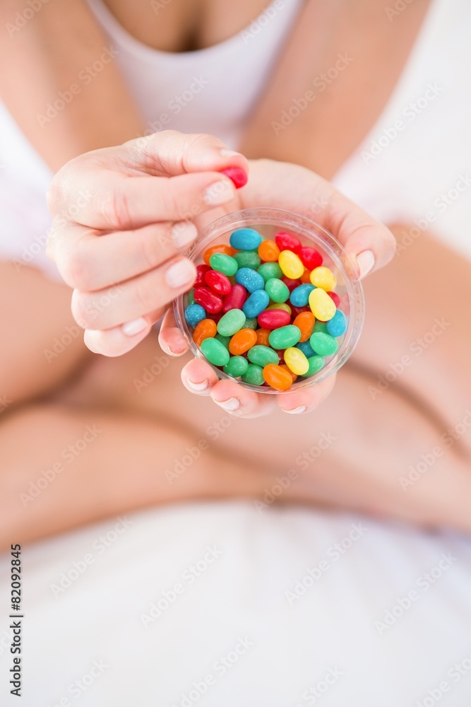 Woman holding candies on bed Woman holding candies on bed